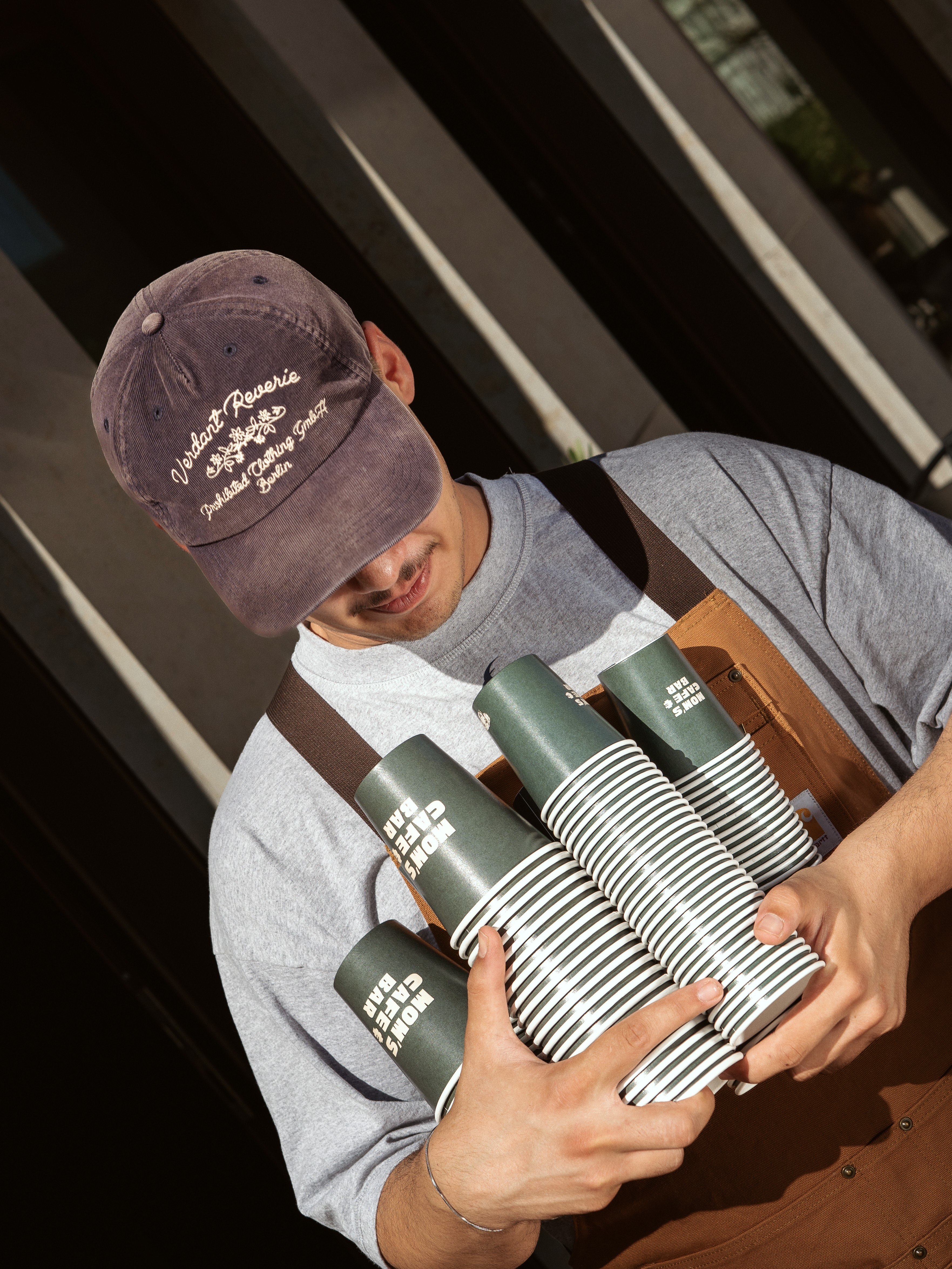 Mitarbeiter hält einen Stapel Mom's To-go-Becher